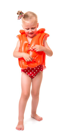Smiling little blond girl in a bathing suit and inflatable vest isolated on white background.の写真素材