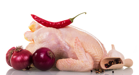 A whole raw chicken carcass, a scoop with various peppers and chili, garlic, onions isolated on white background.の写真素材