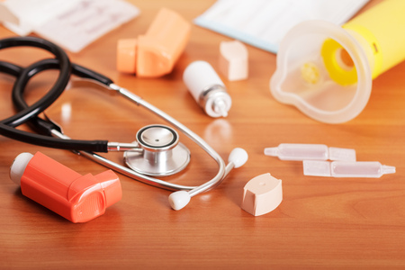 Inhalers aerosol, stethoscope, aerochamber, packaging and medicines on the background of the table.の写真素材