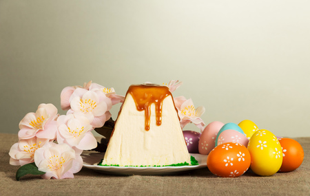 Traditional Easter curds dessert watered glaze, color Easter eggs and branch with flowers on a gray background.の写真素材