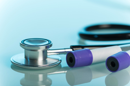 Medical stethoscope and vacuum tubes for blood collection on a blue background.の写真素材