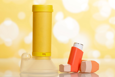 Inhalers and aerochamber on abstract yellow background.の写真素材