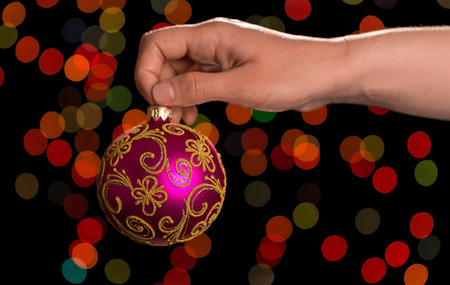 A pink small ball for decoration in the hand, on a dark abstract backgroundの写真素材