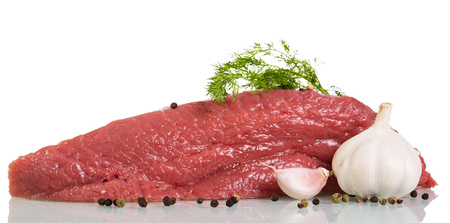 A piece of raw beef, spices, garlic and dill isolated on white background.の写真素材