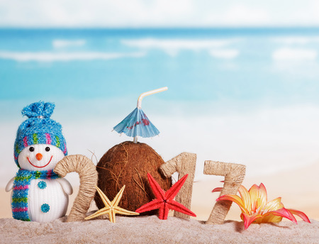 Figures 2017 twined with with string, coconut instead of the numbers 0, snowman, starfish, flower in the sand against the sea.の写真素材