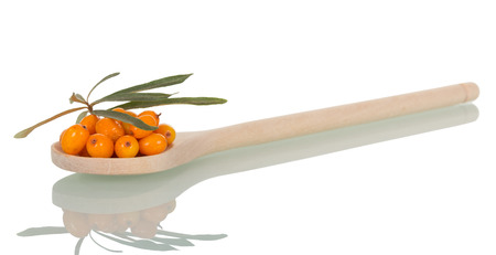 Ripe sea-buckthorn berries and in a wooden spoon and leaves isolated on white background.の写真素材