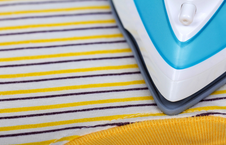 Iron for ironing on the ironing board and striped clothesの写真素材