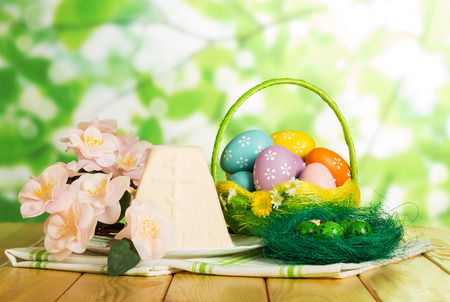 Colored Easter eggs in the basket and on the nest, Easter cheesecake dessert, flowers on abstract green background.の写真素材