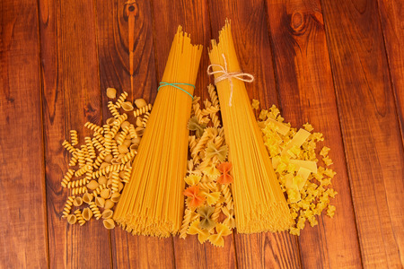 Two bunches of spaghetti and a variety of pasta on a dark wood background.の写真素材