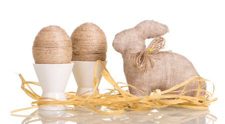 Easter eggs in cups with string entwined and the Easter Bunny, ribbons, isolated on white background.の写真素材