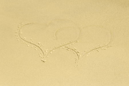 Sea coast. Inscription two hearts on a sandy beachの写真素材