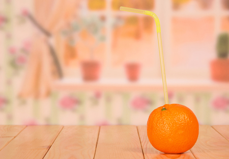 Ripe fresh orange and a straw closeup on the background of the kitchen.の写真素材