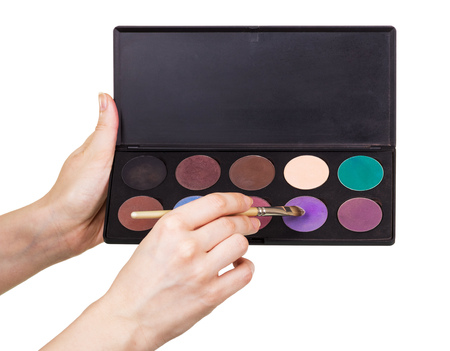Female hands holding a set of colorful eye shadow and cosmetic brush isolated on white background.の写真素材