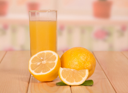 A ripe lemon half, a slice and a glass of juice closeup on the background of the kitchen.の写真素材