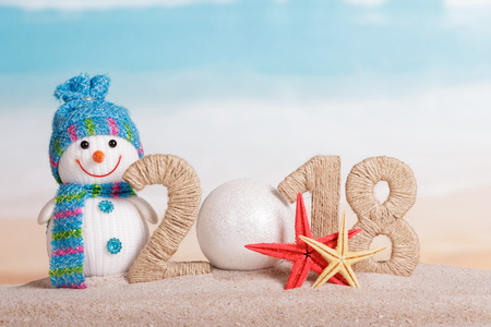 New Year inscription 2018, instead of the number 0 - white ball, snowman and starfish in the sand on the beach.の写真素材
