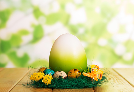 Colorful Easter eggs in the nest and one big on abstract green background.の写真素材