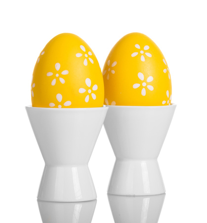Yellow with pattern easter eggs in cups isolated on white background.の写真素材