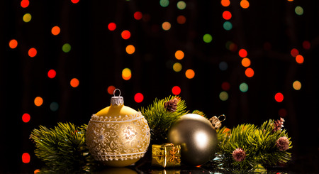 Two bright balls, a box with a gift, pine branches on a dark flickering backgroundの写真素材