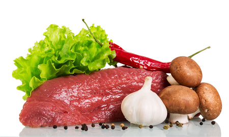 A piece of raw beef, mushrooms, lettuce, garlic and black pepper isolated on white background.の写真素材