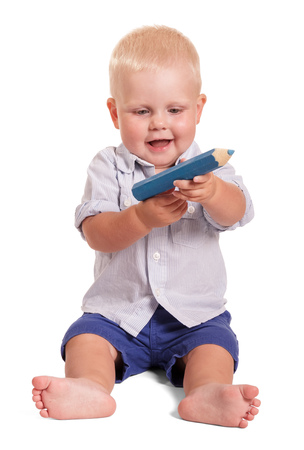 Sitting a little boy holds large pencil isolated on white background.の写真素材