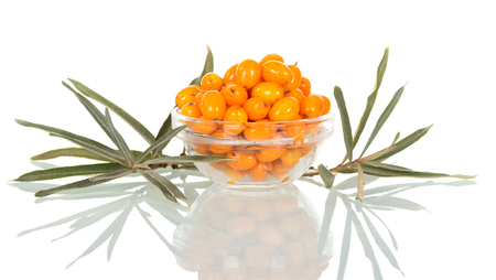 A bowl of ripe sea-buckthorn berries and leaves isolated on white background.の写真素材