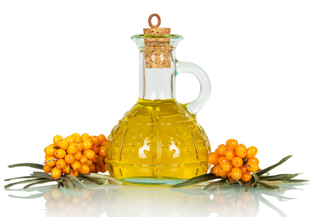 Branches with berries of sea-buckthorn and a bottle of oil isolated on white background.の写真素材