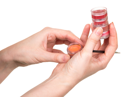 In the female hands, jars with lip gloss and a brush on a white background.の写真素材