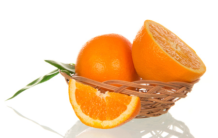Whole orange and juicy slices in a basket isolated on white backgroundの写真素材