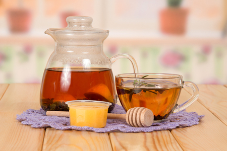 Jug and cup with hot tea and honey, napkin on a wooden tableの写真素材
