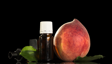 Aromatic liquid for smoking an electronic cigarette and juicy peach isolated on black backgroundの写真素材