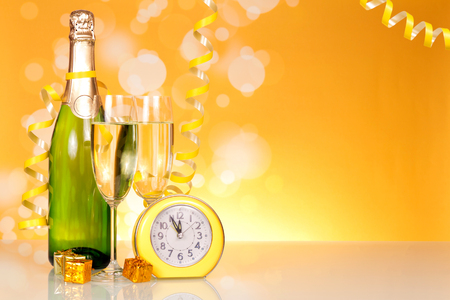 Waiting for the holiday, bottle of champagne and clock on  table backgroundの写真素材