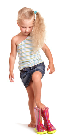 Charming little blonde putting on rubber boots isolated on white background.の写真素材