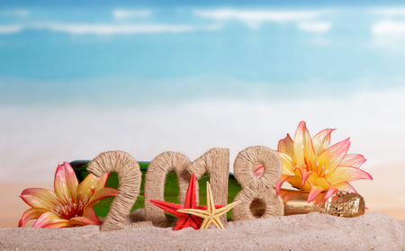 New Year inscription 2018, a bottle of champagne decorated with flowers, and starfish in the sand on the beach.の写真素材
