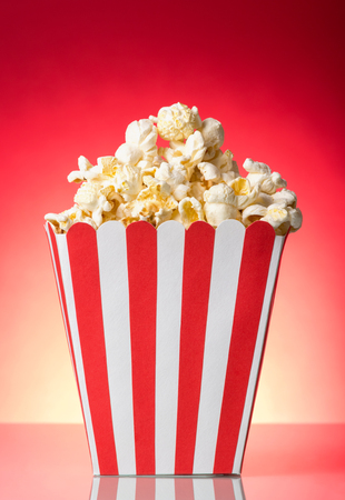 Salty popcorn in large square box on bright red background.の写真素材