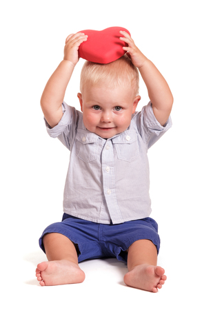 Charming baby holding a red heart in hands over head, isolated on white backgroundの写真素材