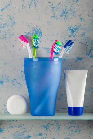 Toothbrushes in the glass and oral hygiene products on shelf in bathroomの写真素材