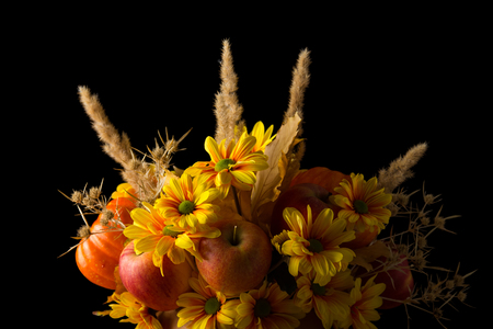 Fall bouquet from chrysanthemums, apples and pumpkins isolated on black backgroundの写真素材