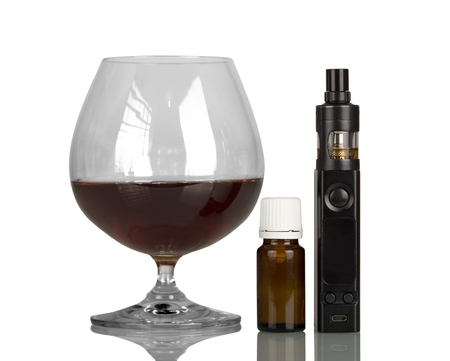 Glass of whiskey and an electronic cigarette, bottle with fragrant liquid, isolated on white backgroundの写真素材