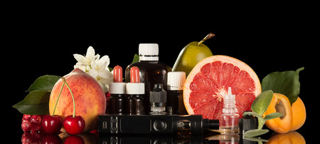 Electric cigarette, set of various liquids for smoking and fresh fruit isolated on black backgroundの写真素材
