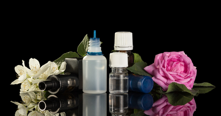 Electronic cigarette and a set of liquids for smoking with floral scent isolated on black backgroundの写真素材