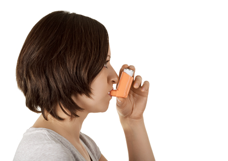 Woman using inhaler and medication relieves asthma attack isolated on white background.の写真素材