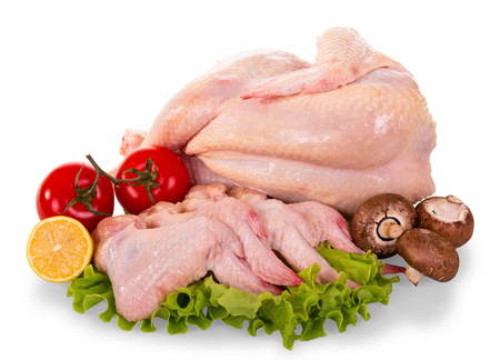 A whole raw chicken carcass and wings, tomatoes, mushrooms, lemon and lettuce leaves isolated on white background.の写真素材