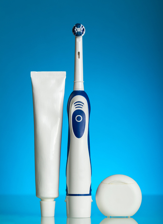 Electric brush for oral hygiene, toothpaste and thread, on blue backgroundの写真素材