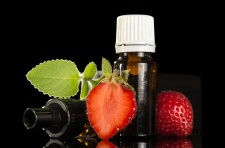 Liquid with fruity scent for smoking an electronic cigarette isolated on black backgroundの写真素材