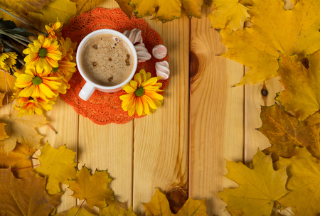 Cup with coffee and sweets on table in frame of yellow autumn leavesの写真素材