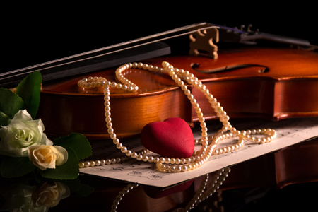 Violin, music notes and a pearl necklace isolated on black backgroundの写真素材