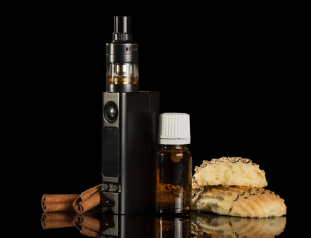 A smoking device, liquid with vanilla flavor and biscuits, isolated on black backgroundの写真素材