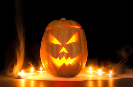 Scary halloween pumpkin jack-o-lanterns isolated on black background lit with small round candlesの写真素材