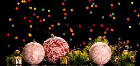 Bright Christmas balls with lace, small gifts and pine branches with cones, on the dark shimmering backgroundの写真素材