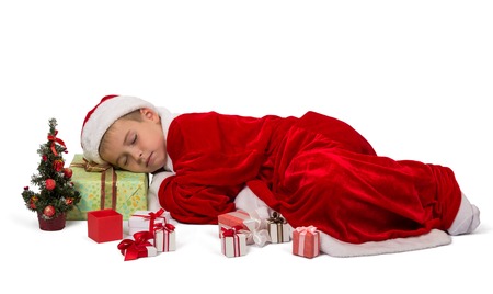 Young boy in festive New Year's suit fell asleep on box with gift, isolated on white backgroundの写真素材